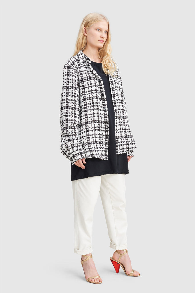 A woman is wearing a black and white checked tweed overshirt by Faith Connexion, a brand of luxury clothes