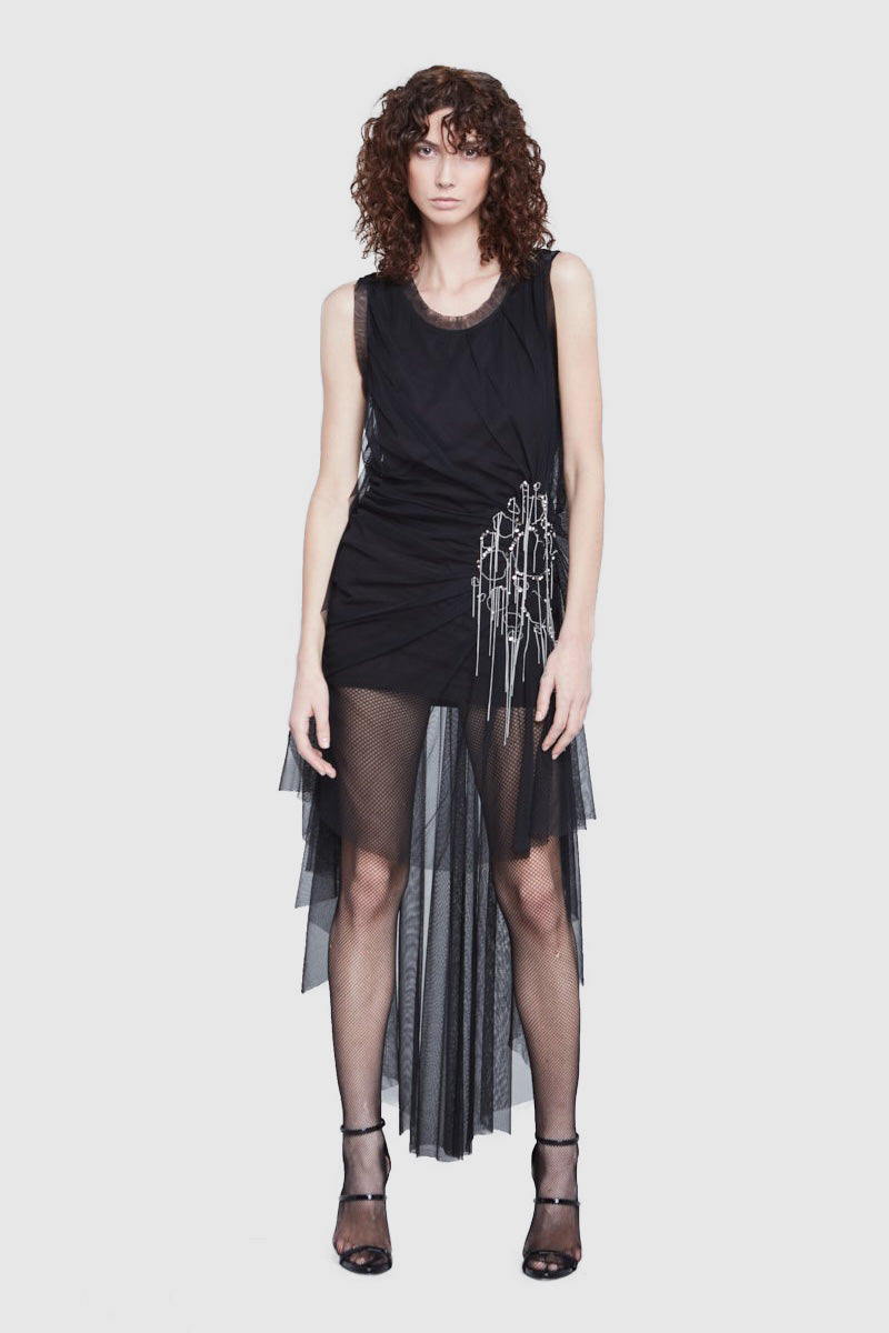 A woman is wearing a black embroidered drap dress by Faith Connexion, a brand of luxury clothes