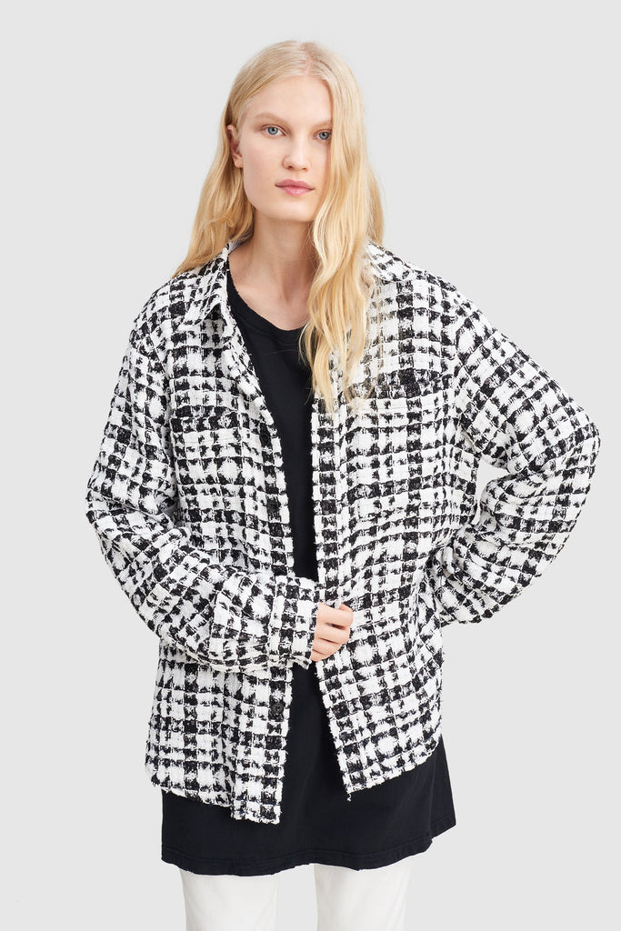 A woman is wearing a black and white checked tweed overshirt by Faith Connexion, a brand of luxury clothes
